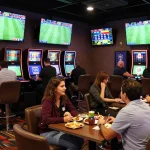 Engaged bettors reviewing odds on a trang cá độ bóng đá uy tín site in a lively sports bar setting.